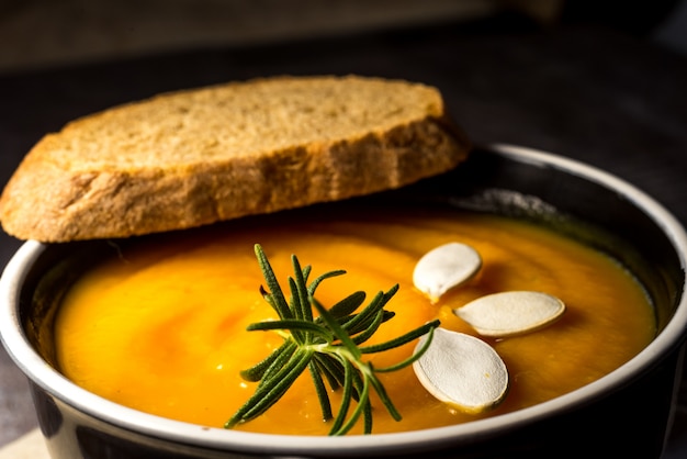 saludable crema de calabaza en una rústica mesa de madera. Sopa de crema de calabaza de otoño con hierbas de romero y picatostes. Copia espacio