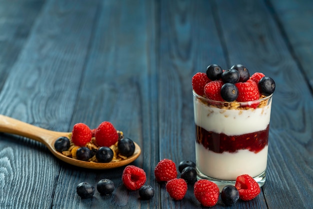 Foto el saludable desayuno de yogur con muesli, mermelada de frambuesa granola y frutas frescas frambuesa y arándano.