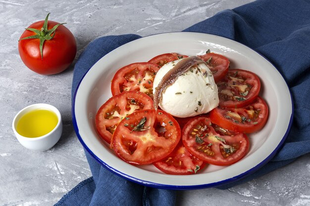 Foto saludable ensalada casera de tomate con mozzarella, anchoas y orégano