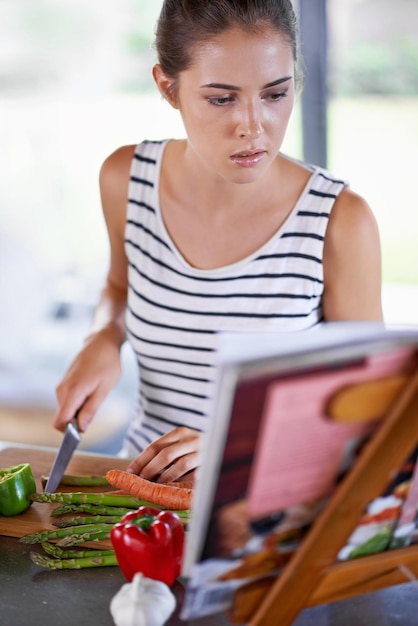 Saludable está en el menú de esta noche Fotografía de una niña cocinando en una cocina