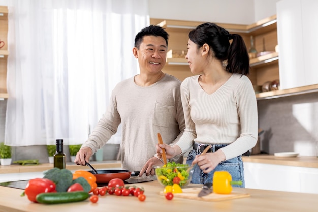 Saludable familia asiática de vegetarianos preparando comida deliciosa