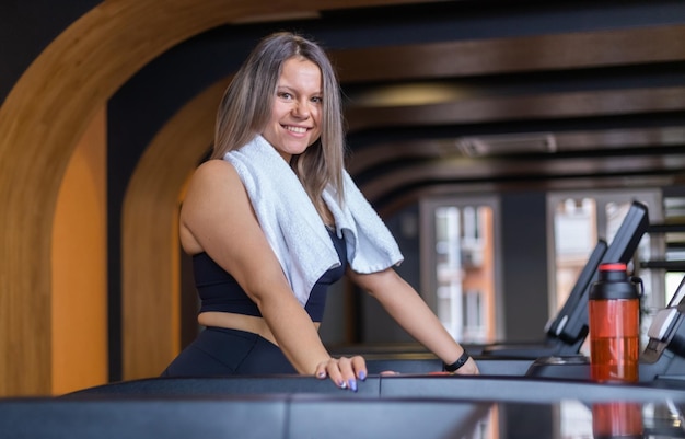 Saludable mujer fitness alegre en ropa deportiva en una caminadora en un gimnasio