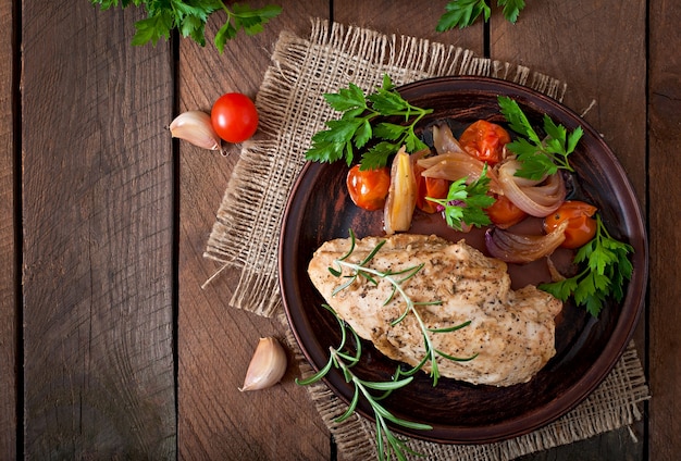 Saludable pechuga de pollo al horno con verduras en un plato de cerámica en un estilo rústico