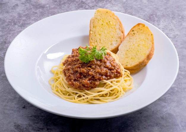 Saludable plato de espagueti italiano cubierto con una sabrosa salsa boloñesa de tomate y carne molida con pan de ajo