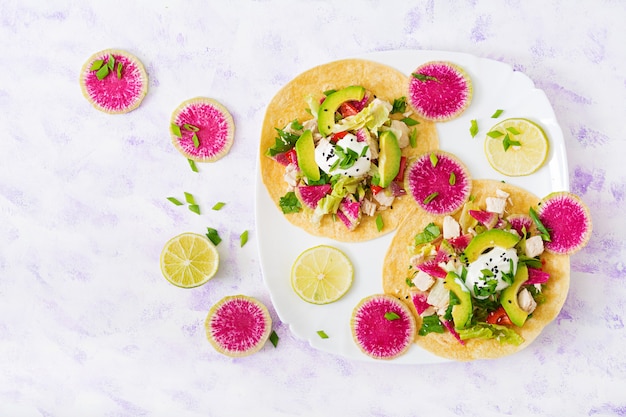 Saludables tacos mexicanos de maíz con pechuga de pollo hervida, aguacate y rábano de sandía y aderezo de yogurt.