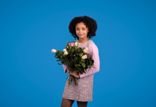 Saludo feliz cumpleaños niño rizado afroamericano positivo con ramo de flores disfruta