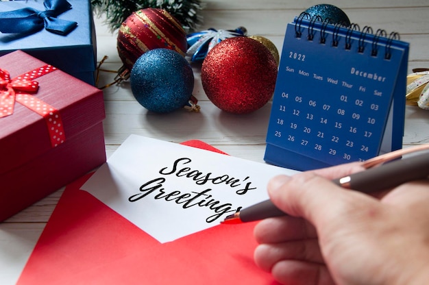 Saludos de la temporada 39 escritos en el bloc de notas en un sobre rojo con decoración navideña y regalos de fondo Celebración navideña