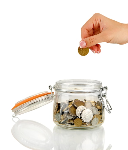 Salvando la mano femenina poniendo una moneda en una botella de vidrio aislada en blanco