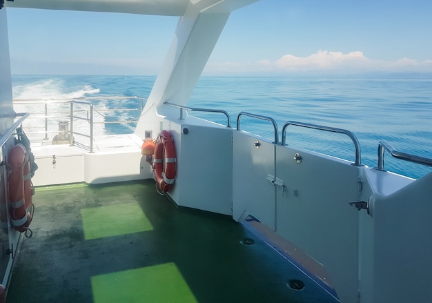 Un salvavidas en la cubierta de un yate de lujo, una vista del mar con olas, un sendero en el agua, el concepto de unas vacaciones en el agua y un viaje romántico.