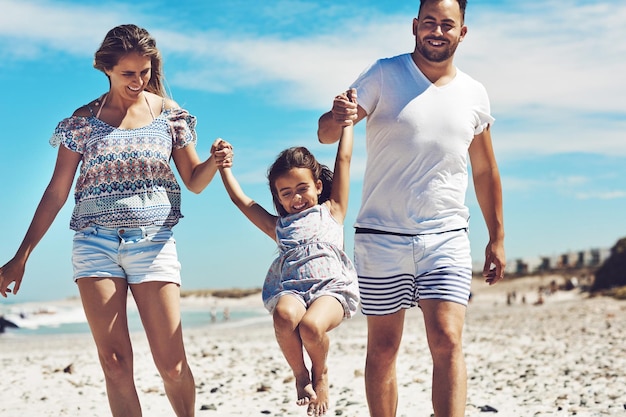 A salvo entre mamá y papá Captura recortada de una joven familia feliz disfrutando de su día en la playa