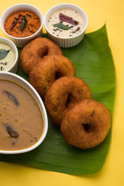 Sambar vada o Medu Vada, una comida popular del sur de la India servida con chutney verde, rojo y de coco sobre un fondo de mal humor. Enfoque selectivo
