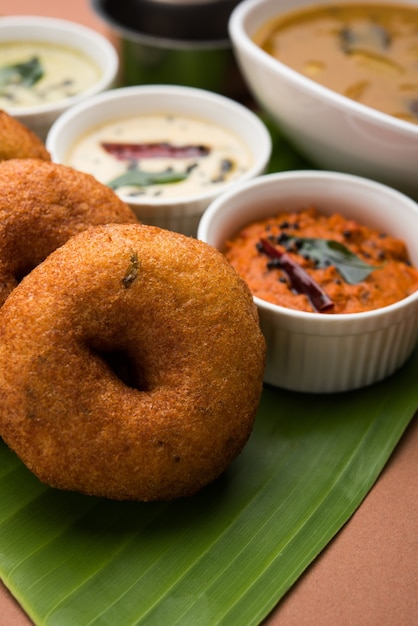 Sambar vada o Medu Vada, una comida popular del sur de la India servida con chutney verde, rojo y de coco sobre un fondo de mal humor. Enfoque selectivo