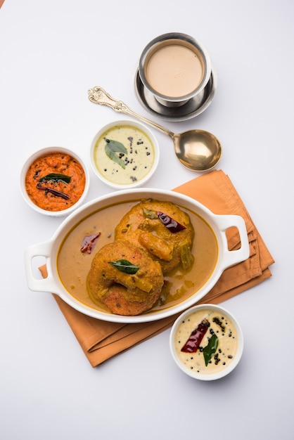 Sambar Vada oder Medu Vada, ein beliebtes südindisches Essen, serviert mit grünem, rotem und Kokos-Chutney auf stimmungsvollem Hintergrund. Selektiver Fokus