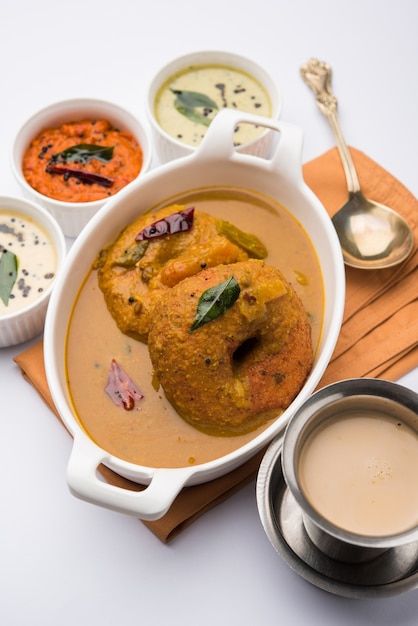 Sambar Vada oder Medu Vada, ein beliebtes südindisches Essen, serviert mit grünem, rotem und Kokos-Chutney auf stimmungsvollem Hintergrund. Selektiver Fokus
