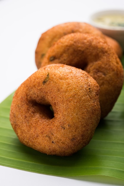 Foto sambar vada ou medu vada, uma comida popular do sul da índia servida com chutney de verde, vermelho e de coco sobre um fundo sombrio. foco seletivo