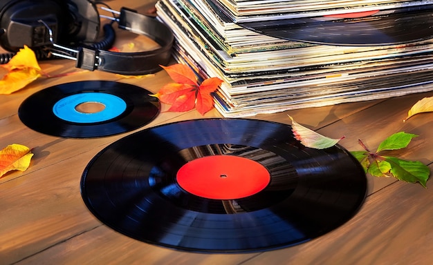 Sammlung alter Schallplatten in einem Stapel mit Kopfhörern und Herbstlaub.