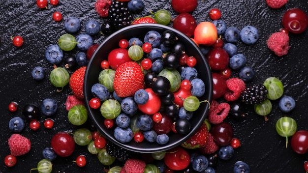 Sammlung frischer wilder Beeren auf schwarzem Holz, Draufsicht