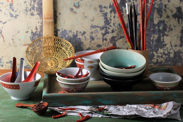Foto sammlung von chinesischen schüsseln und löffeln mit rustikalem hintergrund und sonnengetrocknetem chili
