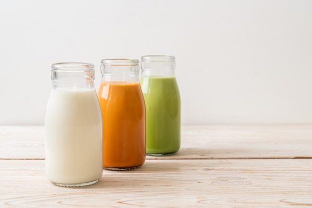 Sammlung von thailändischem Milchtee, Matcha-Grüntee-Latte und frischer Milch in der Flasche auf Holztisch