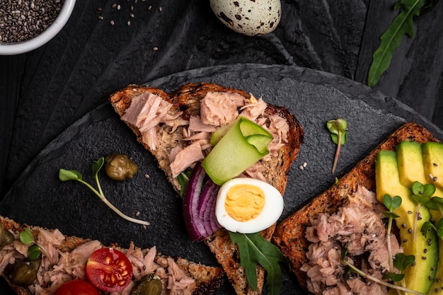 Sammlung von Thunfisch-Bruschetta-Sandwiches Leckeres Frühstück oder Snack Toasts mit Thunfisch, köstliches, gesundes Essen auf dunklem Hintergrund Draufsicht