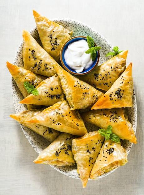 Foto samosa india elaborada con filo con patatas y verduras picantes, servida con yogur, menta y limón. cerrar para publicidad