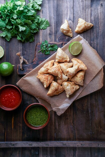 Samosa - massa frita / assada com recheio, petiscos indianos populares, servida em uma tigela com especiarias e coentro fresco em fundo rústico