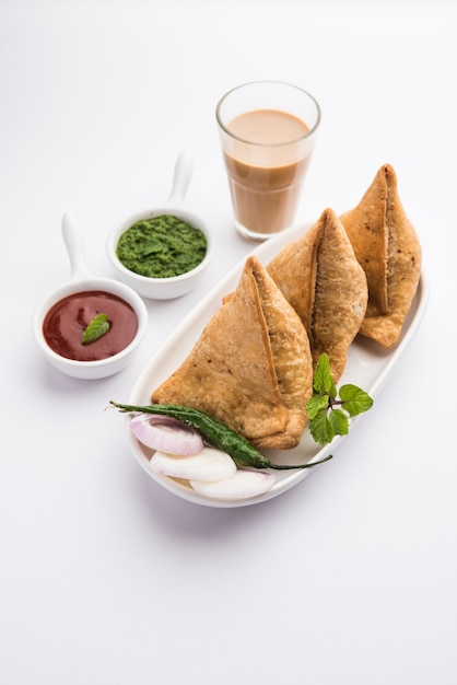 Samosa: pastelería frita / horneada en forma de triángulo con relleno sabroso, refrigerios populares de la hora del té indio, servidos con salsa picante verde y salsa de tomate.