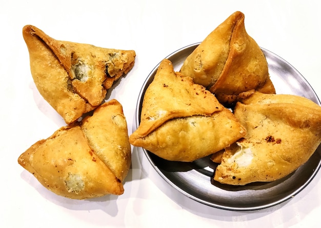 Samosa de patata sobre fondo blanco, comida tradicional de Ramadán indio o paquistaní, comida callejera picante, aperitivos famosos en el país asiático.