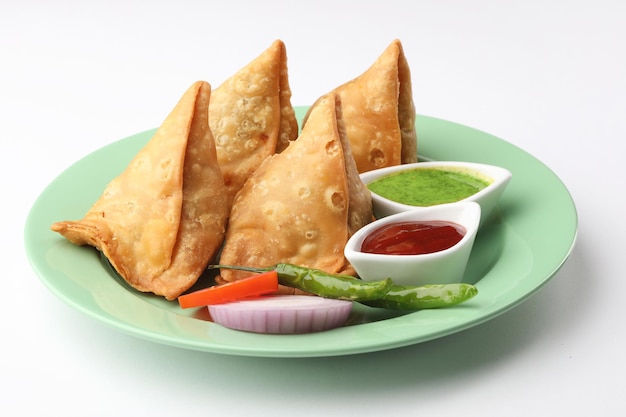 Samosa vegetal servida con cebolla verde y queso picante