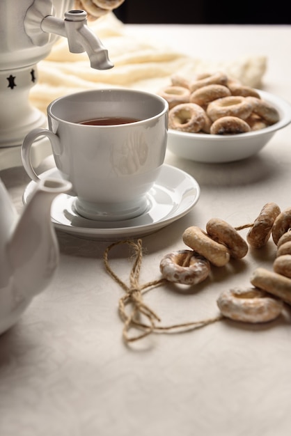 Un samovar con bagels y té caliente sobre el mantel blanco.