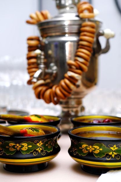 Samovar de tradición rusa con panecillos y platos folclóricos rusos de Khokhloma con mermelada en la mesa