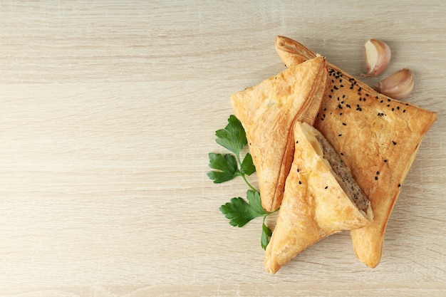 Samsa dorado con ingredientes sobre fondo de madera