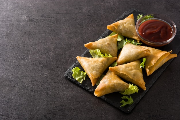 Samsa oder Samosas mit Fleisch und Gemüse auf Schwarz. Traditionelles indisches Essen.