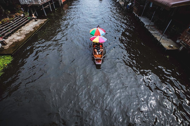 Foto samut songkhram tailândia 05 de novembro de 2023 barcos de madeira ocupados transportando pessoas no mercado flutuante de amphawa um método popular tradicional de compra e venda ainda é praticado nos canais de amphawa