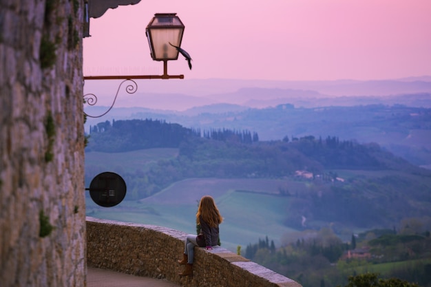 San gimignano. garota olhando para a paisagem da toscana com colinas e ciprestes ao amanhecer