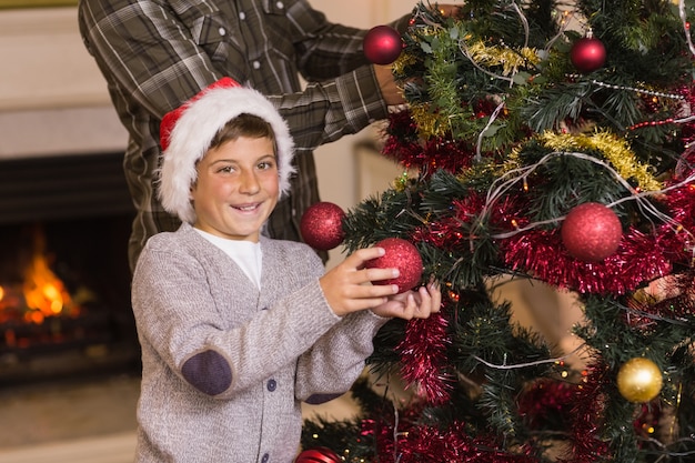 San und Vater dekorieren den Weihnachtsbaum