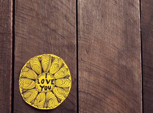 San Valentín amarillo con inscripción sobre fondo de madera