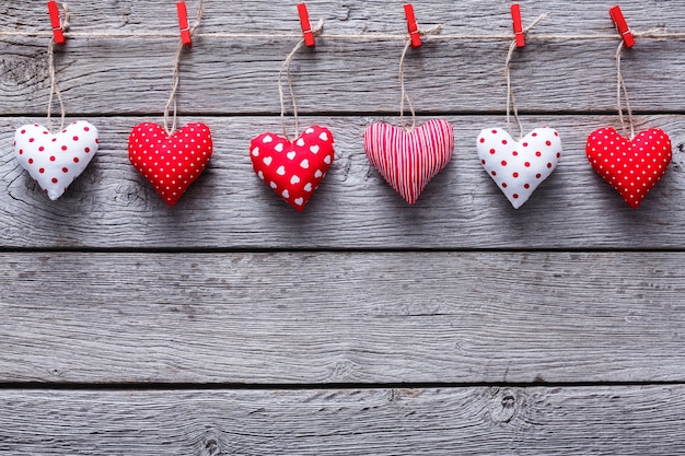 San Valentín con borde de fila de corazones de almohada cosida bricolaje en pinzas de ropa rojas en tablones de madera gris rústico