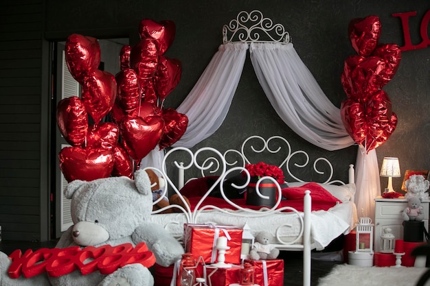 San Valentín en el interior Dormitorio oscuro con una cama blanca decorada con globos rojos