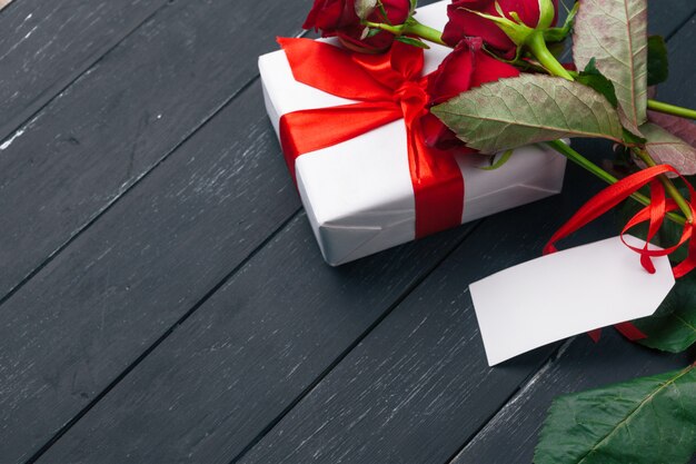 San Valentín, rosas rojas y caja de regalo en mesa de madera