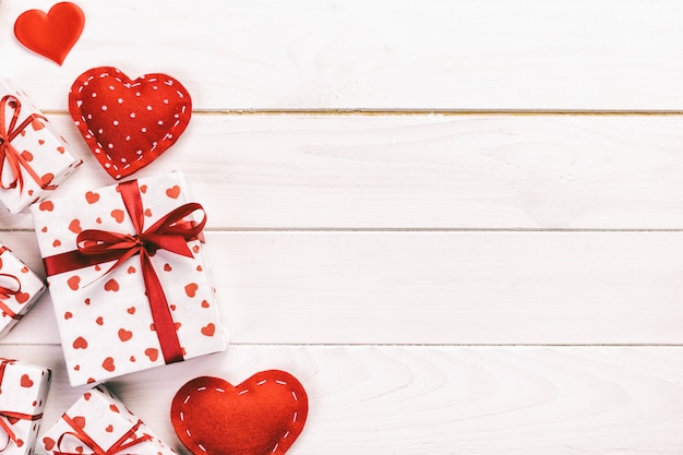 San Valentín u otro regalo hecho a mano en papel con corazones rojos y caja de regalo en envoltorio navideño. Presente caja de regalo en la vista de la mesa de madera con espacio de copia, espacio vacío para el diseño