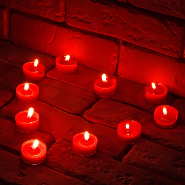 San Valentín Velas encendidas en forma de corazón sobre una superficie de piedra antigua.