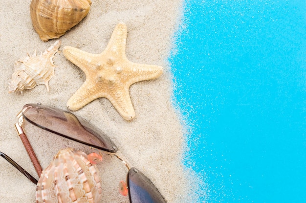 Sand mit Muscheln und Sonnenbrillen auf der blauen Draufsicht Platz für Text kopieren