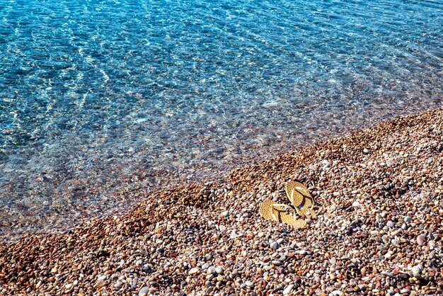 Sandalen am Ufer des Meeres mit Kiesstrand