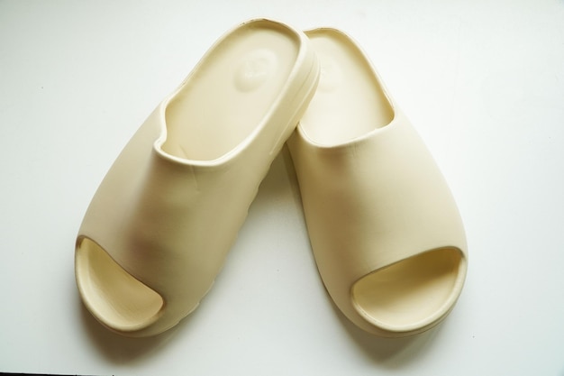 Sandalias de goma de color crema sobre un fondo blanco.