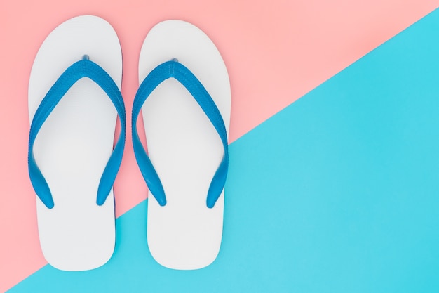 Sandalias de playa de espuma blanca sobre fondo rosa y azul