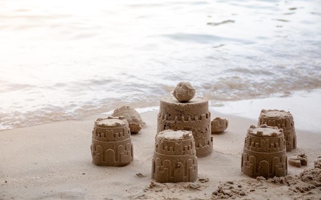 Foto sandburg am strand auf dem hintergrund der meereswelle, die kommt, um die sandburg zurückzuerobern