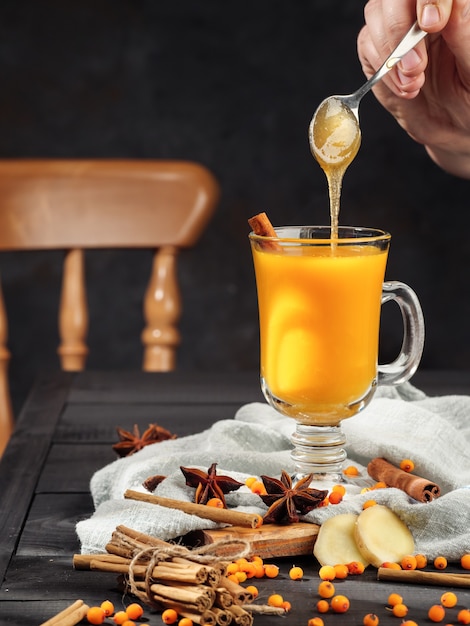 Sanddorn-Tee steht auf einem dunklen Tisch mit Sternanis und Zimt.