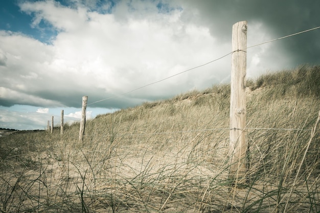 Sanddüne und Zaun an einem Strand, Insel Re, Frankreich. Bewölkter Hintergrund