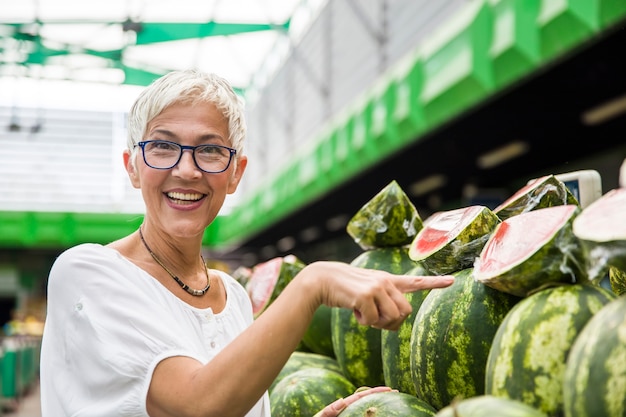 Sandía de compra de la mujer mayor en mercado